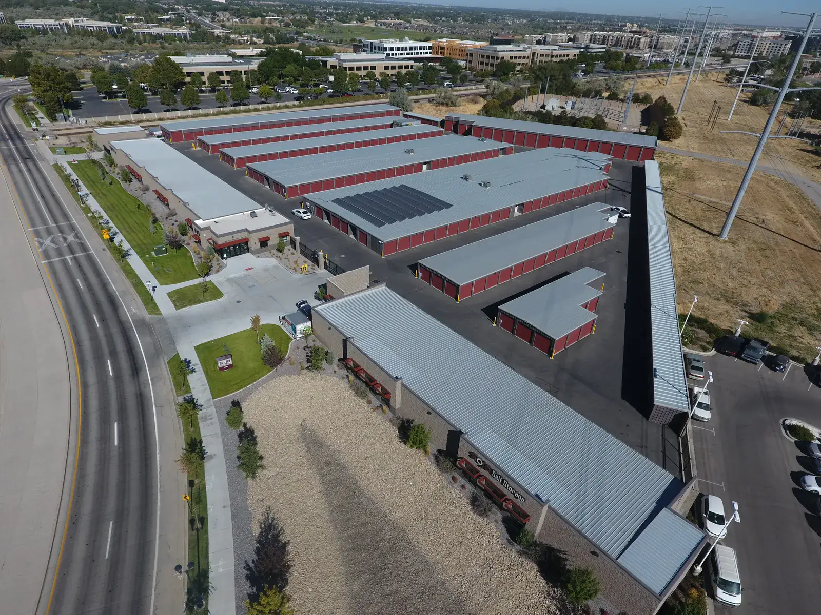 SoJo Self Storage facility aerial in South Jordan, Utah, orange-door steel buildings with the Wasatch range behind